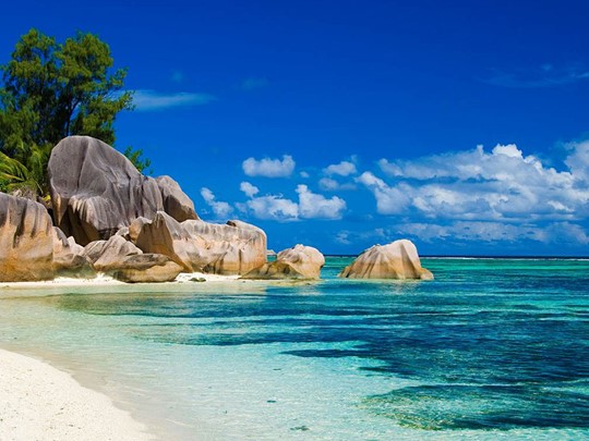 L'emblématique plage d'Anse Lazio dévoile son sable blanc parsemé de roches granitiques au bord d'une eau turquoise 